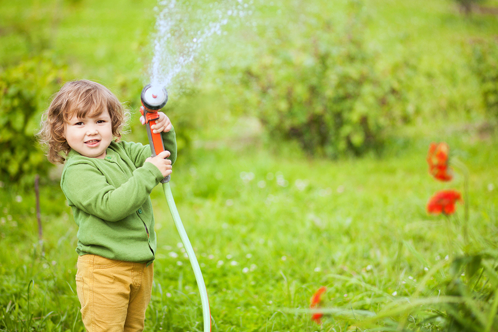 Adorable toddler little helper watering the garden at a preschool & Daycare Childcare Center serving Thornton, CO