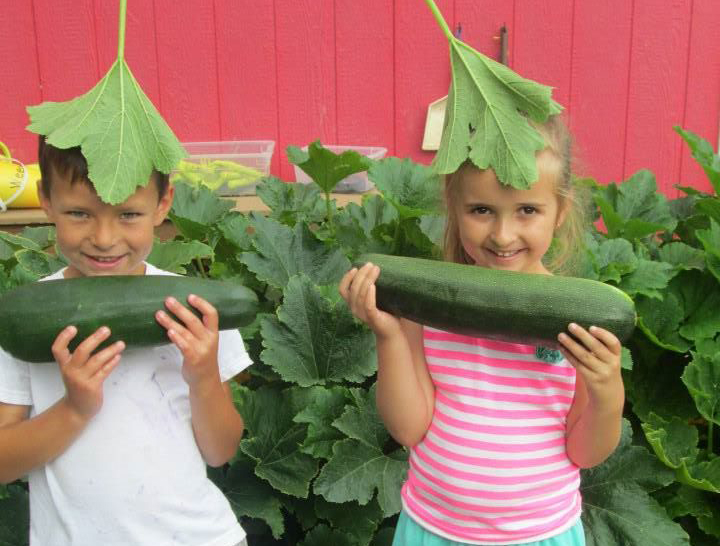 happy boy and girl holding big cucumbers at a Preschool & Daycare Serving Thornton, CO